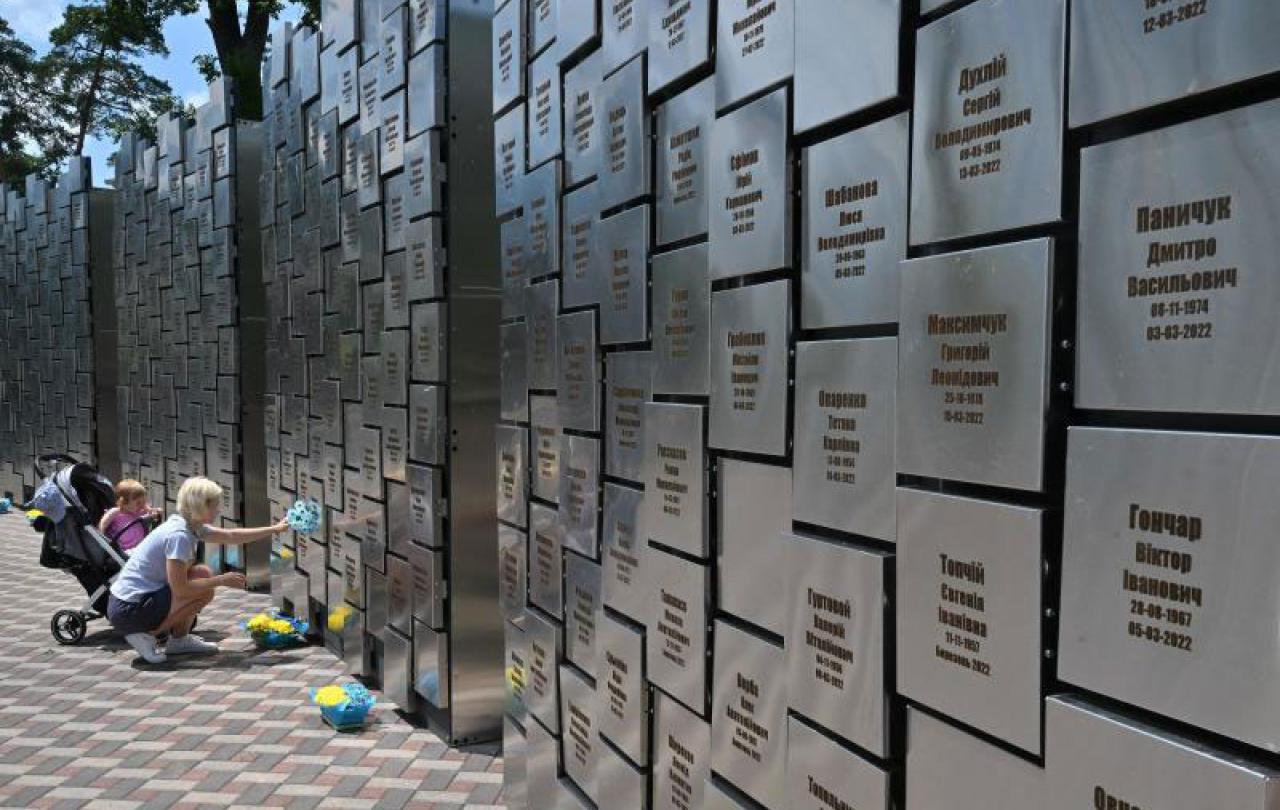 A woman squats and touches a war memorial