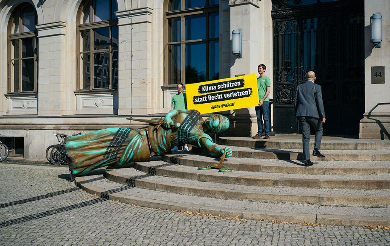 A fallen statute with tyre tracks over it lies on the steps to a government building, in a form of protest.