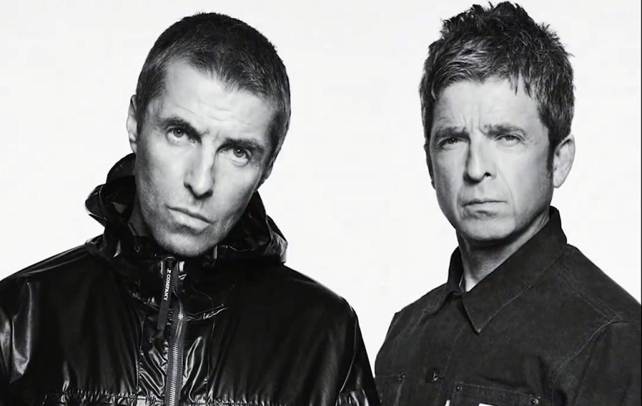 Two middle age rock star brothers pose for the camera in a black and white picture