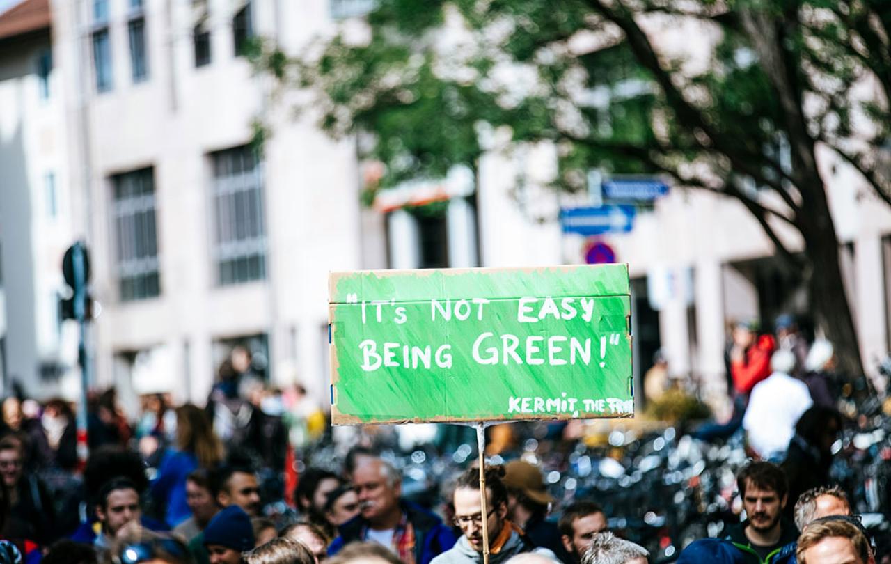 A protester holds up a green sign reading: 'It's hard to be green. Kermit'.