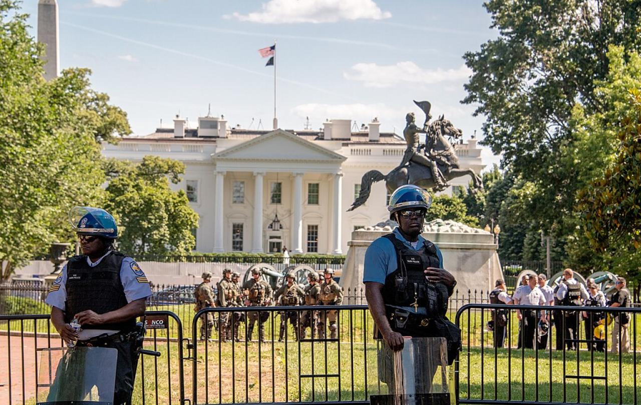 Riot police stand guard outside a White House fence line.