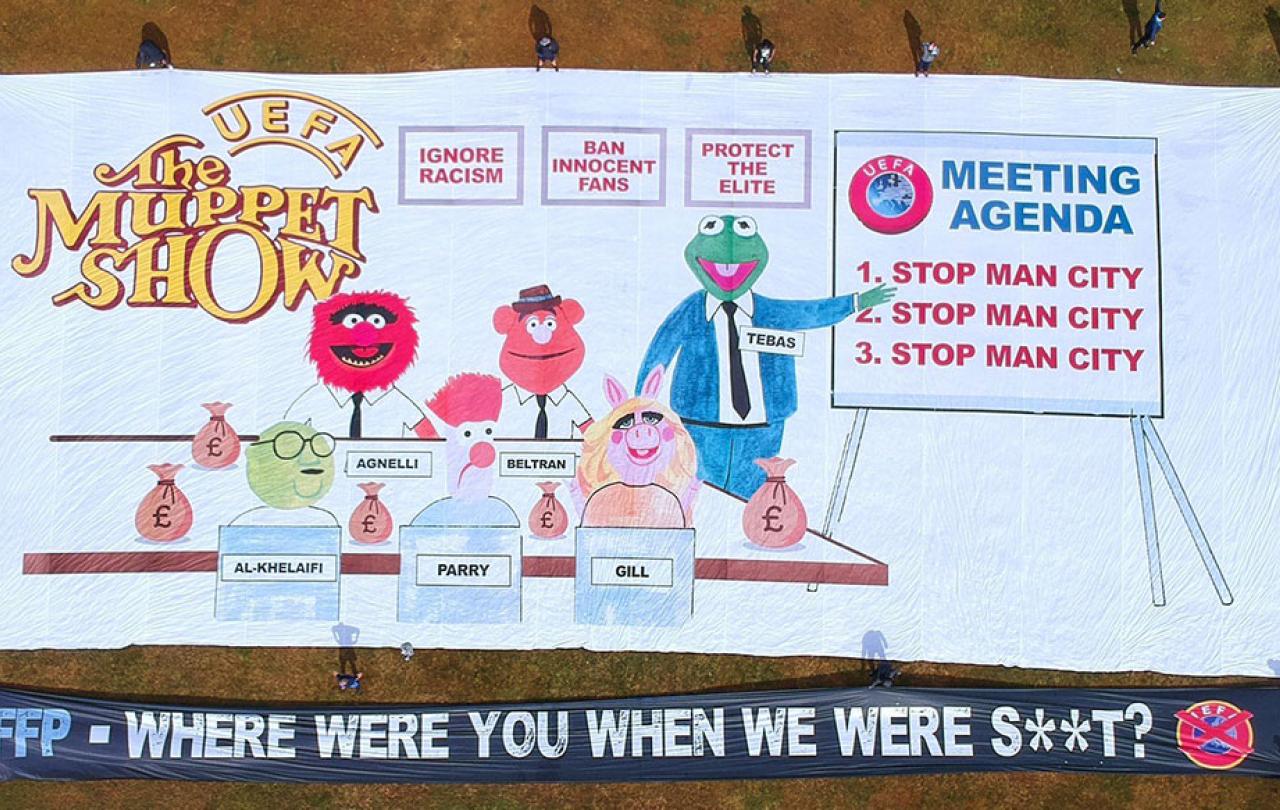 A football support protest banner depicts The Muppet Show logo, a meeting of men in suits and various slogans.