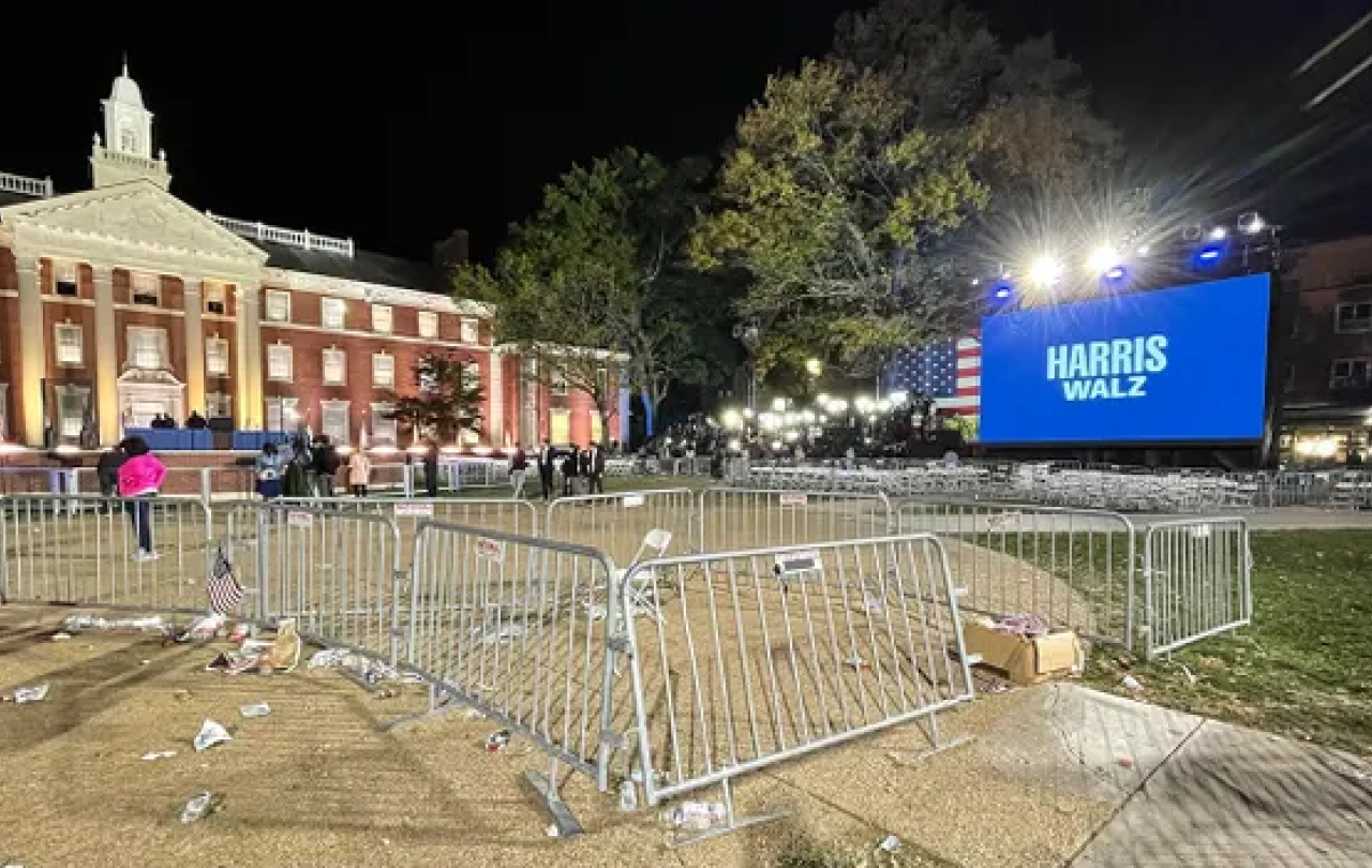 Crowd barrier surround empty space at a night time political rally.