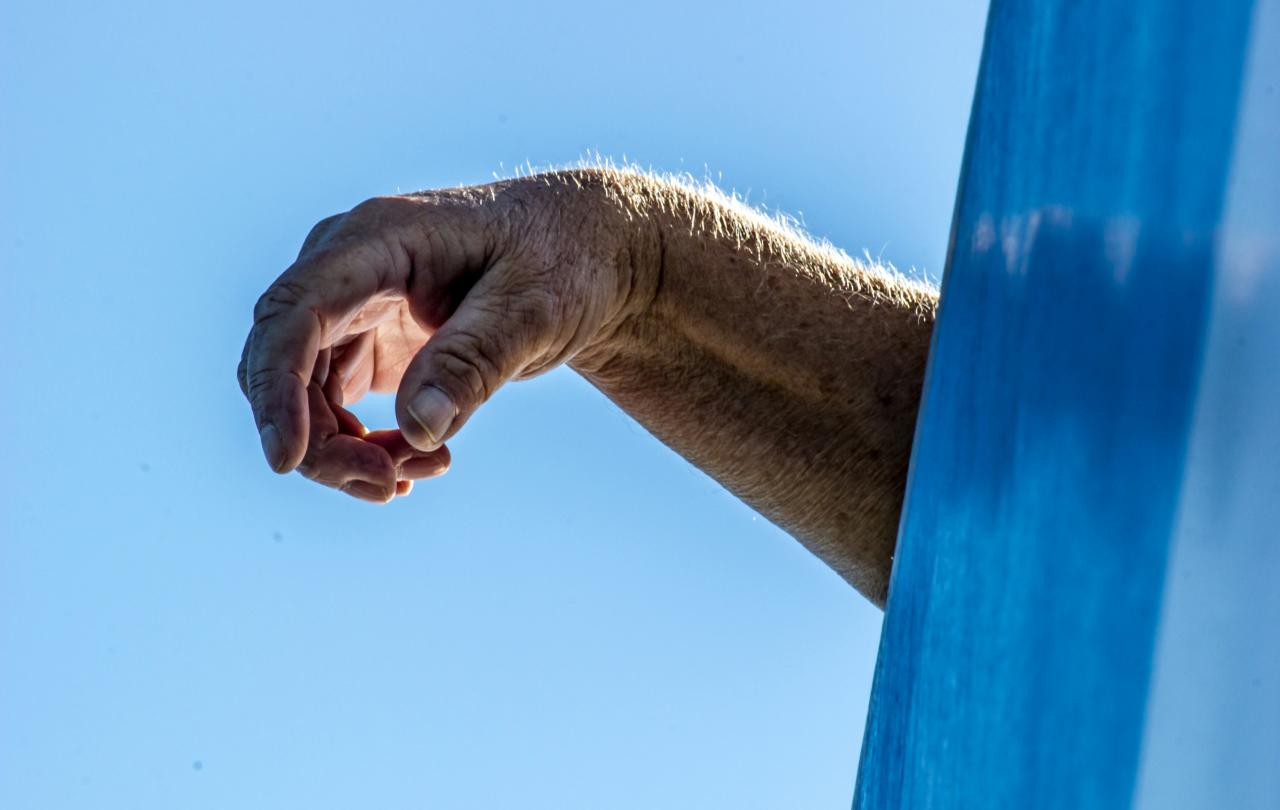 A hand drapes over the side of an object out of shot.