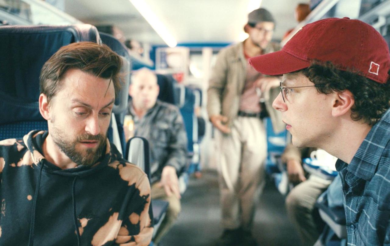Two male cousins converse across the aisle of a train.