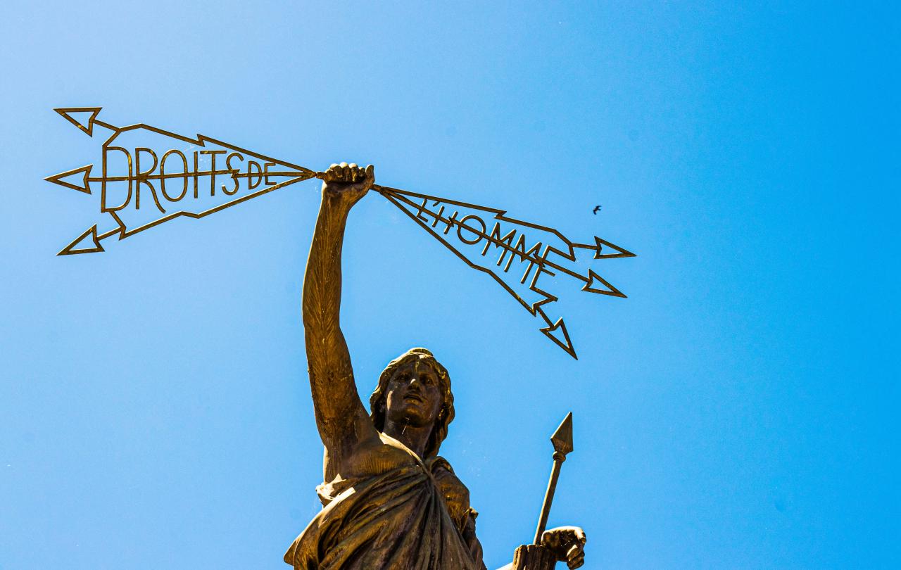A statue of a woman holding a spear in one hand a lightening bolt in the others that reads: 'Droits de l'homme'.
