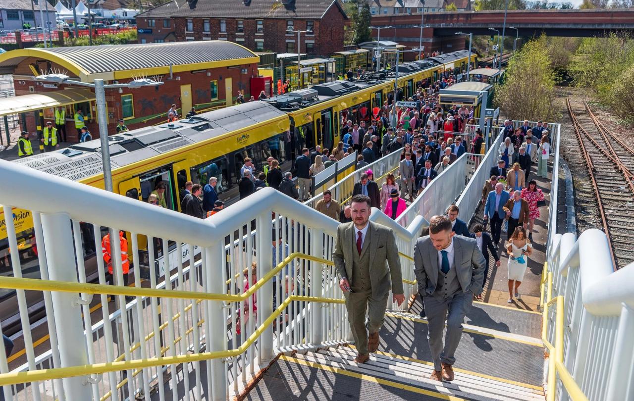 Smartly dressed people crowd a station platform and stairs.