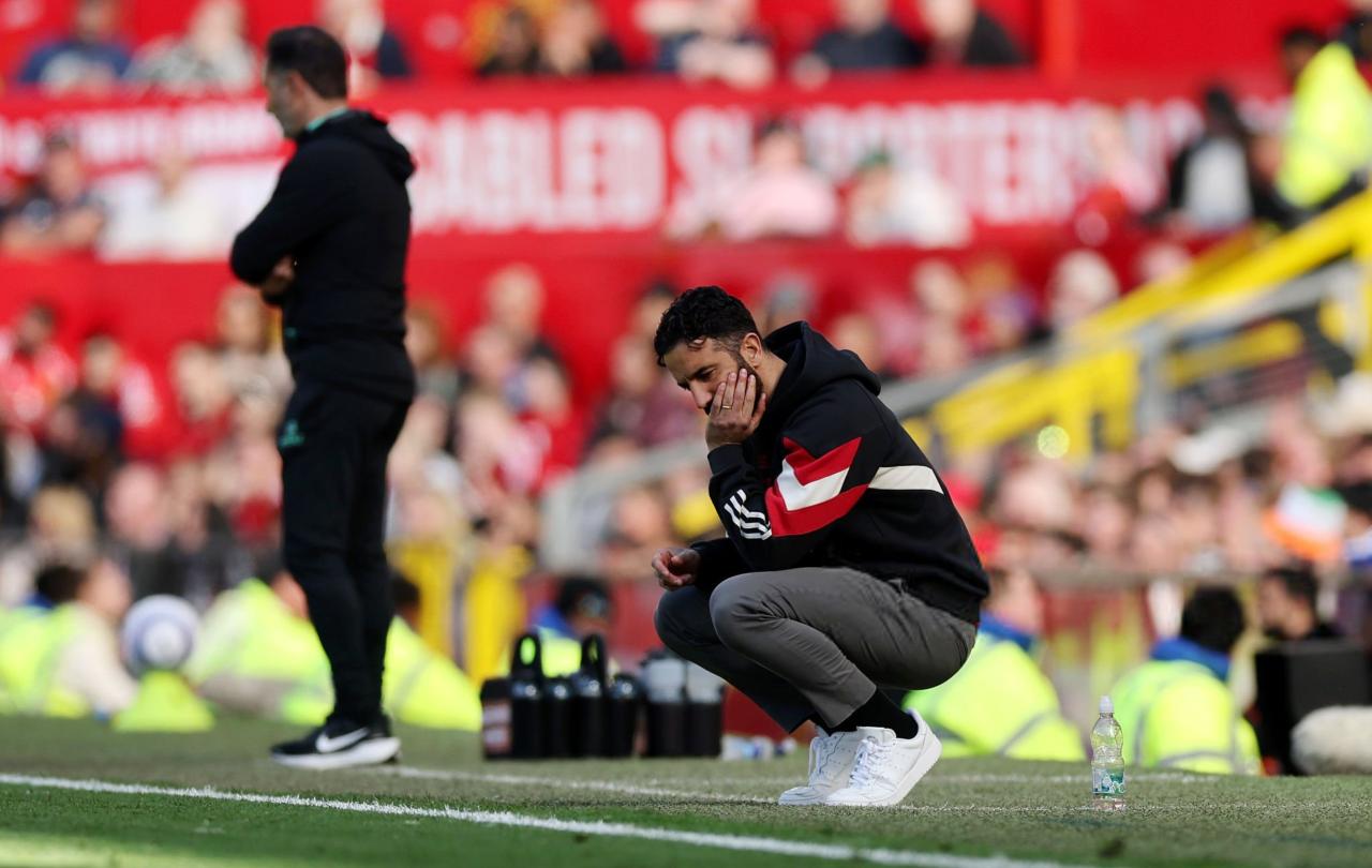 A dejected football coach squats by the byline.