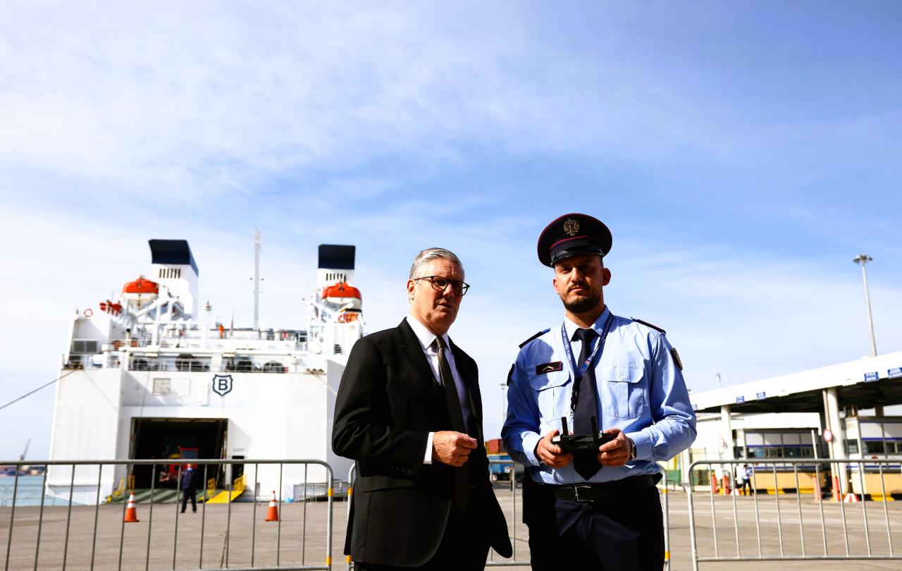 A prime minister stands next to an Albanian police officer in front of a ferry.