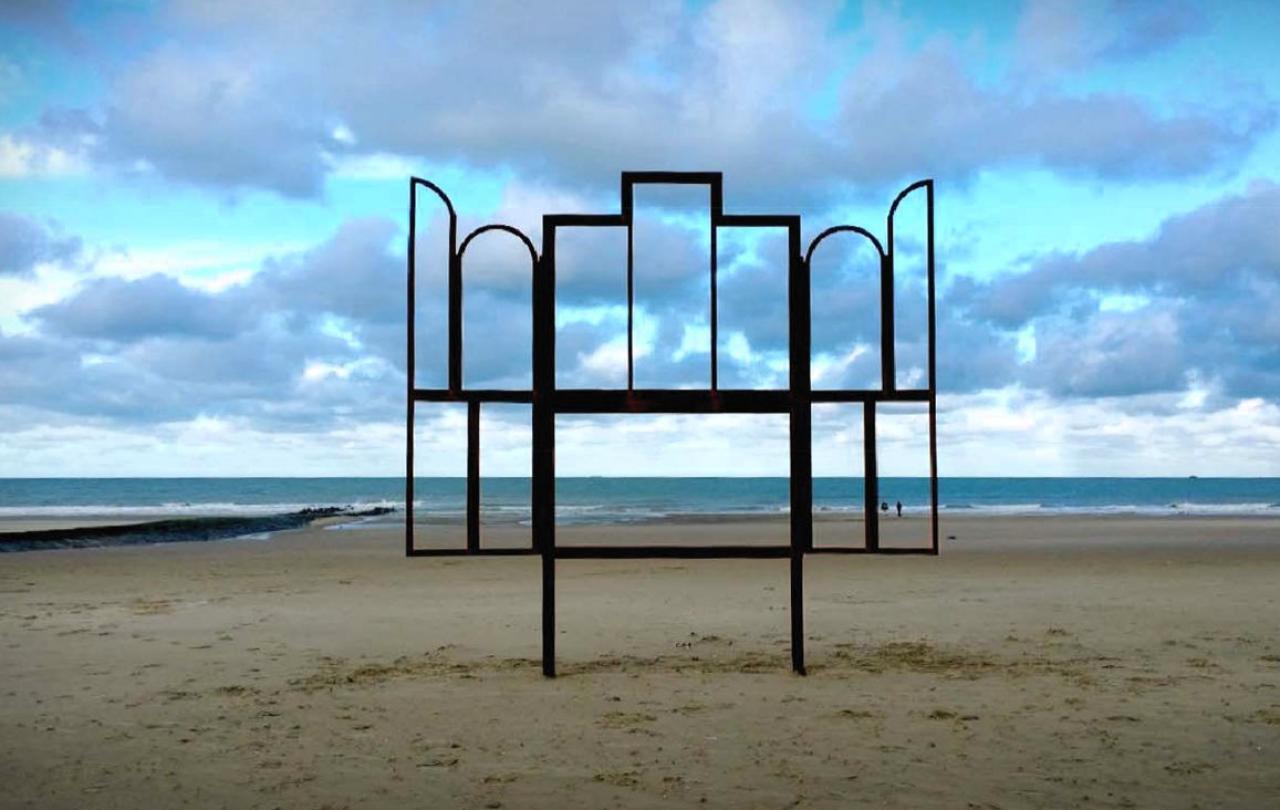 A metak sculpture outlines an altar, stands on a beach.