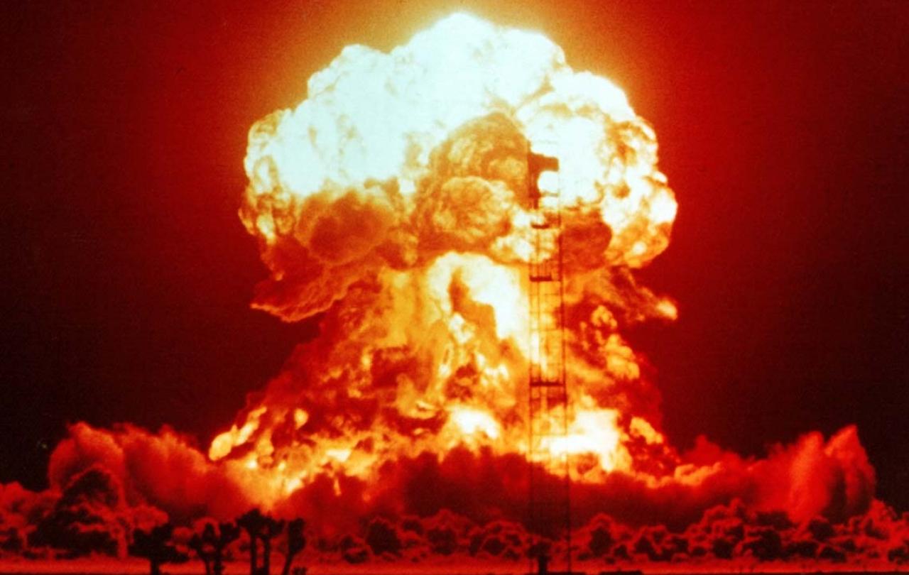 A nuclear explosion glows red and orange against the night sky.