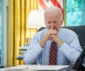 President Biden sits at a desk, holding his balled hands to his mouth.