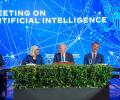 A board of experts sit at a table against a conference backdrop.