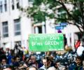 A protester holds up a green sign reading: 'It's hard to be green. Kermit'.