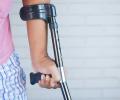 A crutch is held in the hand of someone in pyjamas.