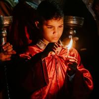 A boy concentrates hard as he holds one candle to another to light it.