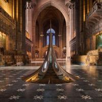 An art structure of a circular peak sits on the chequered floor of a cathedral.