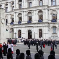 A Remembrance Sunday service stands to attention around a cenotaph.