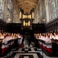 Choristers stand and sing in choir stalls in a church