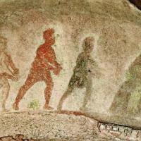 Silhouttes of three wise men approach the Virgin and Child, painted on stone. 